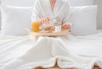 Wall Mural - Young woman having breakfast on bed in hotel room