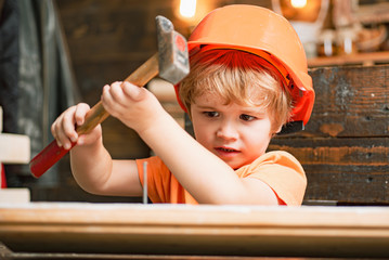 Wall Mural - Kid in hard hat holding wooden plank and hammer. Child engineer with carpenter work hammer on wood.