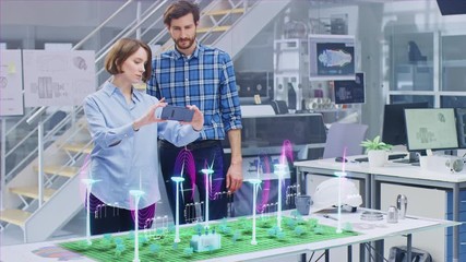 Wall Mural - green energy concept: two ecological engineers use augmented reality smartphone to design 3d wind tu