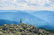 © anatoliy_gleb - Rear view girl tourist opening her arms, standing on top of cliff with powerful view mountain valley with green forests. Girl in bright jacket with long hair is enjoying the scenery at cloudy day.