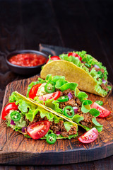 Wall Mural - Taco shells with lettuce, ground beef meat,  mashed avocado, tomato, red onion and jalapeno pepper, on wooden board, vertical, copy space