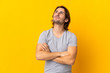 © luismolinero - Young handsome man isolated on yellow background looking up while smiling