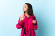 © luismolinero - Young latin woman with backpack and trekking poles isolated on blue background making stop gesture and disappointed