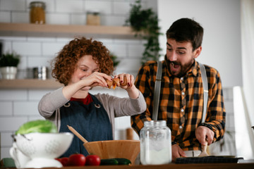 Wall Mural - Young couple making delicious food at home. Loving couple enjoying in the kitchen..