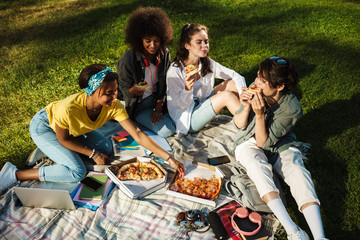 Image of funny nice student girls eating pizza while doing homework