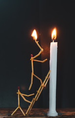 Wall Mural - Matchsticks in form of a man lighting a candle, matchstick man lighting a candle.