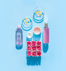 Poster - Composition of natural cosmetic products and glasses with daisies, bottles, tubes and flowers on light blue background. Summer skin care concept. Top view . Spa or wellness