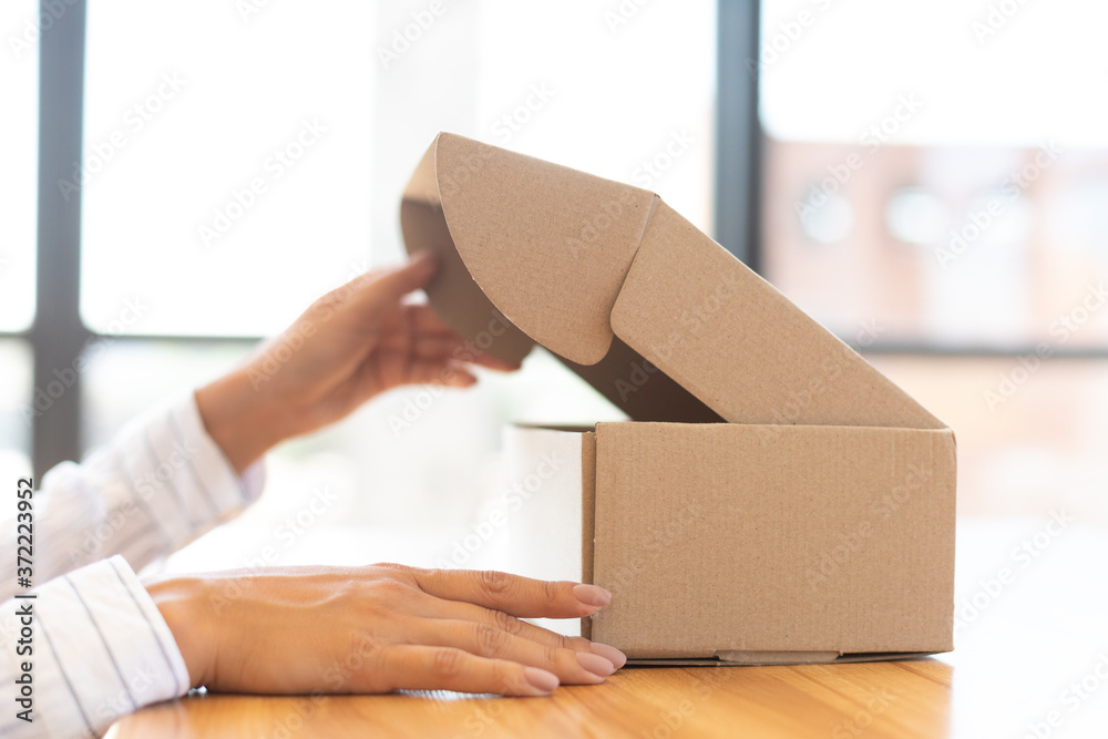 Lady opening box with new parcel, close-up