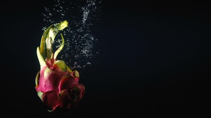 Wall Mural - Shooting of falling pitaya in the water on black background