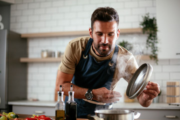 Portrait of handsome man in kitchen. Young man having fun while cooking at home