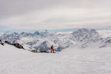 Fototapeta Natura - a snowboarder standing on a ski slope with a mountain view