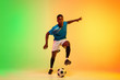 © master1305 - Leader. African-american male soccer, football player training in action isolated on gradient studio background in neon light. Concept of motion, action, ahievements, healthy lifestyle. Youth culture.