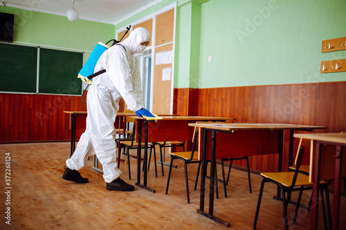 Cuadros en Lienzo A man from disinfection group cleans up the desk at school with a yellow rag