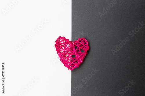 Pink wooden heart on black and white paper background, love and romance symbol, valentine concept background