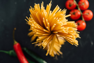 Wall Mural - selective focus of raw Italian spaghetti and vegetables isolated on black