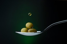 Green Olives On A Spoon On A Dark Background, A Drop Of Olive Oil