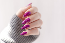 Female Hand With Violet Purple Long Nails And Nail Polish Bottle