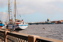 Sailing Ship On The Neva River In Saint Petersburg On A Sunny Day, The Dome Of St. Isaac's Cathedral On The Horizon