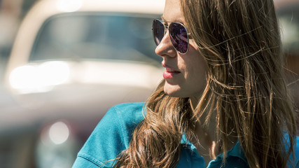 Wall Mural - Happy caucasian woman walking on the street on a bright sunny day. Cheerful stylish girl with sunglasses enjoying, relaxing in a good mood