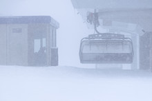 Empty Ski Resort Chair Lift Under Very Snoy Weather And  Control Cabin With Empoee Sitting. Weather In Ski Resort And Cancelations Due To Bad Weather.