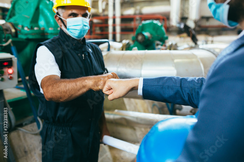 Cuadros en Lienzo businessman and worker handshake indoor industry plant, covid protected with fac