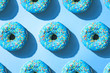 Blue donuts flat lay pattern, on top of blue background with hard shadow.