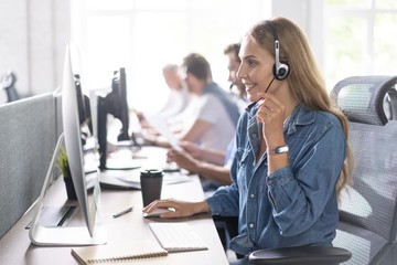 Canvas Print - How can I help you? Beautiful call center workers in headphones are working at modern office.