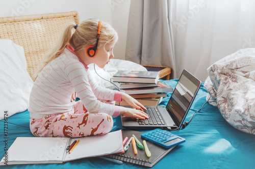 Caucasian girl child learning online on laptop. Virtual Internet class school on video call during self isolation quarantine at home. Distant remote education class. A new normal and homeschooling.