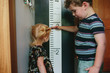 © Maria Manco/Stocksy - brother measure little sister on growth chart
