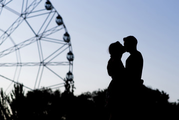 Silhouette of a couple in love on the background of a ferris wheel