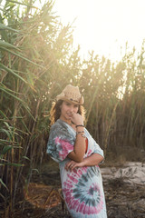 Chica joven con sombrero posando ferente a unos juncos