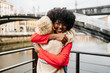 © Sergio Marcos/Stocksy - Happy multiracial best friends hugging on street
