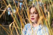 Cheerful European Young Woman On A Field Of Dried Grass At Sunset