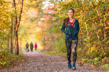 Woman Walking In Autumn Forest Nature Path Walk On Trail Woods Background. Happy Girl Relaxing On Active Outdoor Activity.
