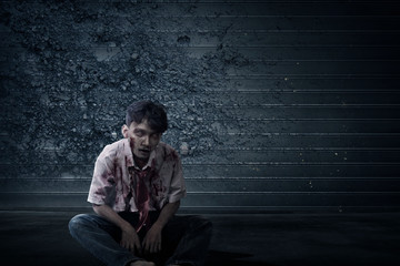 Poster - Scary zombie with blood and wound on his body sitting