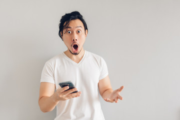 Surprised and shocked long hair Asian man in white t-shirt is using smartphone.