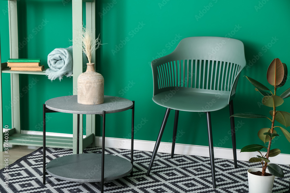 Armchair with table near color wall in room