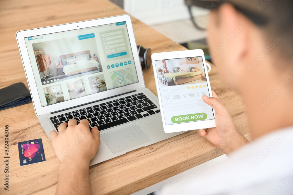 Man with tablet computer booking room in hotel online at home