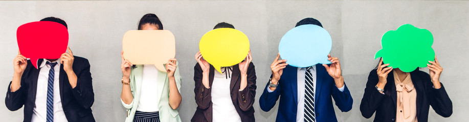 Group of business people holding a empty copyspace speech bubble icon while standing against grey background