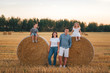 © Irina84 - A family of four have rest near a haystack in a wheat field in summer at sunset time.