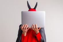 Stylish Caucasian Man In Devil Hat With Horns And Vampire Cape With Laptop Isolated On White Backhround.