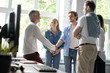 © opolja - Welcome to our team! Business men in smart casual wear shaking hands while working in the creative office