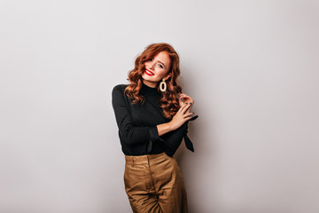 Cute long-haired white girl posing with smile. Gorgeous ginger lady in black blouse expressing happiness.