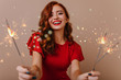 © Look! - Adorable white woman posing with bengal lights. Gorgeous red-haired girl holding sparklers and laughing in new year.