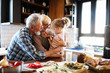 © NDABCREATIVITY - Happy grandparents with grandchildren making breakfast in kitchen