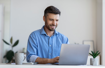 Poster - Handsome male entrepreneur working on laptop at desk in modern office