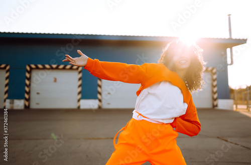 Fotomural Young African American woman - dancer dancing in the street at sunset
