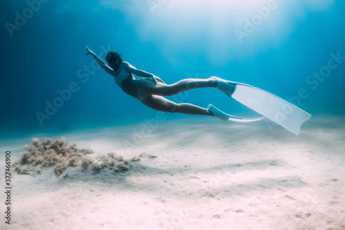 Attractive woman freediver glides and posing over sandy bottom with fins Poster Mural XXL