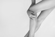 Black and white photo of smooth woman's legs after laser epilation and hand on a knee. Treatment, tenderness, epilation concept 