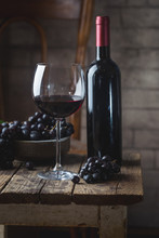 Red Wine In A Glass And Ripe Grapes On Wooden Table